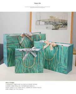 Groene cadeautassen van papier met gouden patronen en strikken voor mooie verpakkingen.