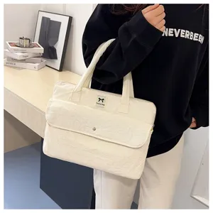 Detailansicht der cremeweißen gepolsterten Laptoptasche mit Vordertasche und Griffen im Alltag.