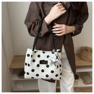 Vista dettagliata di una elegante borsa tote a pois bianchi e neri con manici intrecciati.