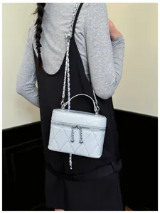 Detail view of light blue quilted vanity chain bag with woven strap and top handle.
