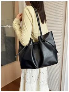 Vista di dettaglio di una borsa a spalla nera morbida con nodo coulisse, accessorio versatile.