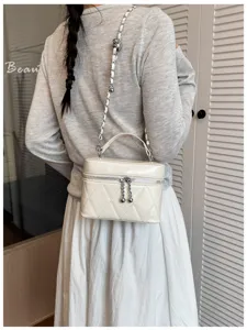 Detailed view of the stylish white quilted vanity bag with chain strap and top handle.
