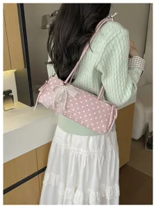 Vista dettagliata della borsa a baguette a pois rosa con elegante fiocco in pizzo e perle.