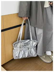 Dettaglio borsa a spalla plissettata argentata, borsa tote Y2K con ciondolo di perle.