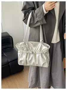 Vista dettagliata della borsa a spalla bianca arricciata, elegante shopper con fibbia chic.