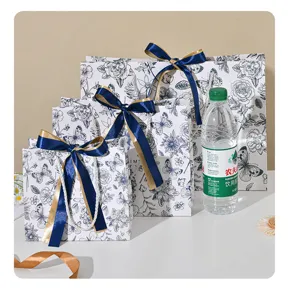 Gedetailleerd overzicht van bloemige geschenkzakjes met blauwe linten op witte tafel.
