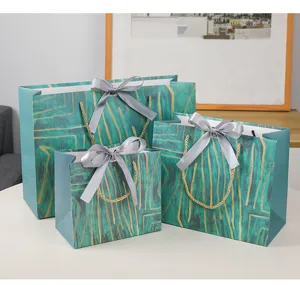Detailweergave van papieren cadeauzakjes met groen en goud patroon en grijze strikken.