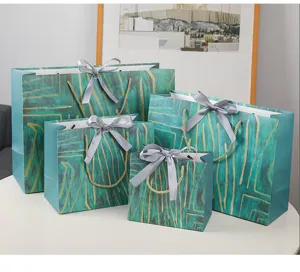 Gedetailleerd overzicht van luxe groene papieren cadeautassen met gouden patroon en strik.