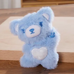 Blue plush bear pendant with white heart embroidery, cute cartoon doll bag accessory detail.