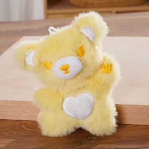Detailed view of the cute yellow plush bear keychain featuring a white heart and embroidery.