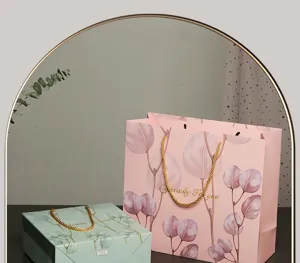 Sacchetti regalo in carta di alta qualità con foglie di eucalipto e manici dorati per cosmetici.
