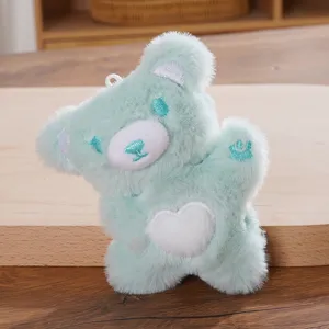 Cute mint green plush bear pendant detail view featuring white heart embroidery on the soft belly.
