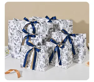 Elegante papierencadeautassen met bloemen en blauwe linten voor feestdagen.