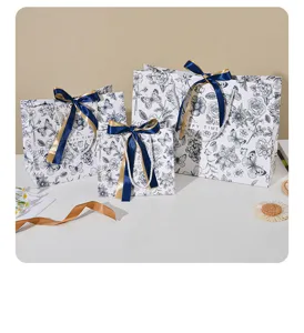 Elegante blauw-witte papieren cadeauzakjes met bloemenmotief en strikken voor feestelijke dagen.