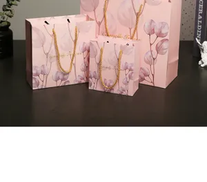 Eleganti sacchetti regalo rosa in carta con stampa di eucalipto e manici dorati per feste.