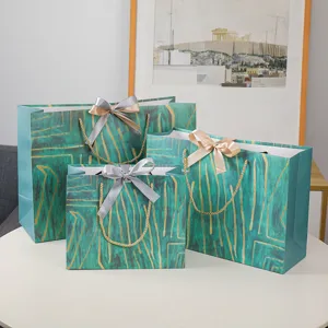 Groene geschenken papieren tassen set met gouden abstract patroon en strikken voor verpakking.