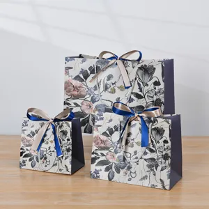 Set van elegante papieren cadeauzakjes met bloemenprint en strikken voor feestjes.