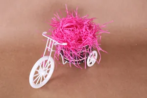 Felroze opvulmateriaal voor geschenkdozen, gepresenteerd met een wit ijzeren driewielermodel.