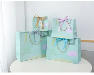 Detail van mintgroene papieren cadeauzakjes met elegante linten en artistieke patronen.
