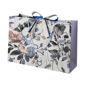 Elegante sacchetto regalo in carta floreale con fiocco in nastro e manici per boutique.