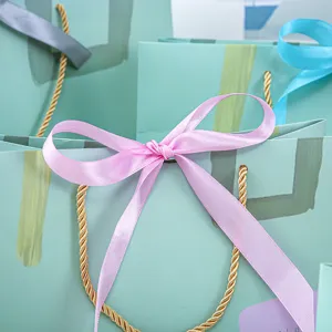Frisse artistieke geschenkpapieren tas met gouden touwgrepen en elegante roze strik.