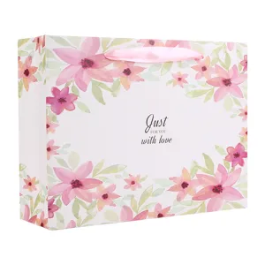 Papieren geschenkzak met aquarel bloemmotief en roze lint handvatten voor verjaardag