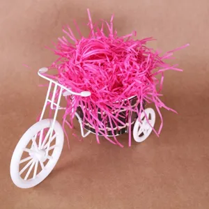 Felroze gekreukt papier als opvulling voor geschenkdozen, getoond in witte fietsstandaard.