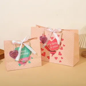 Set di sacchetti regalo in carta rosa con fiocchi bianchi per feste di compleanno.