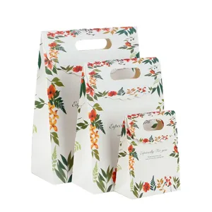 Set van drie elegante papieren cadeautasjes met bloemmotief en handvat voor feestdagen.