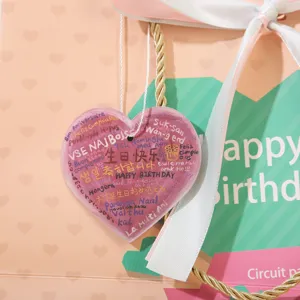 Primo piano dettagliato di una borsa regalo rosa con etichetta a cuore e auguri multilingue.