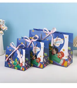 Detailed view of blue cartoon space gift bags with pink bows and rope handles for kids party.