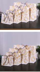 Elegante wit-gouden bloemige geschenkpapieren tassen met grijze strikken voor verpakking.