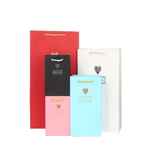 Detailweergave van gekleurde papieren cadeautasjes set met handgrepen en hartversiering.