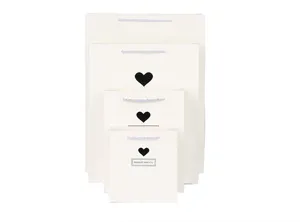Set van witte papieren cadeautjes met zwarte hartjes en handgrepen, detailweergave.