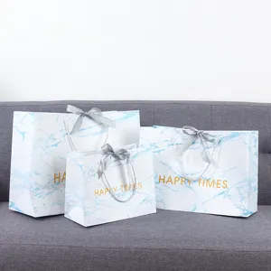 Marmer patroon papieren geschenkzakken met blauw design en grijze lint handgrepen voor detailhandel.