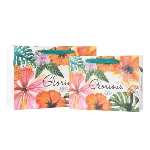 Tropical floral paper shopping gift bags with ribbon handles for retail and presents.