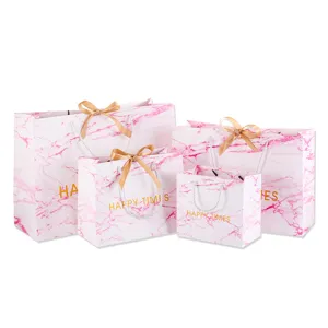 Roze marmer patroon papieren geschenktassen met gouden strikken, elegante verpakking voor feest.