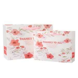 Close-up detail of floral paper gift bags, elegant pink watercolor flower prints with ribbon.