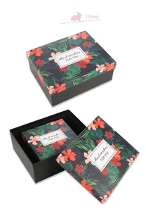 Gedetailleerd uitzicht op zwarte geschenkdozen met tropisch bloemmotief en wensen.
