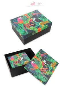 Detailopname van de tropische jungle cadeaubos met papegaaienmotief en gouden logo-etikett.
