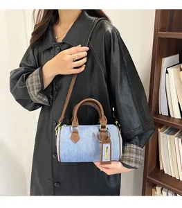 Detail view of the stylish denim boston shoulder bag worn with leather jacket in casual setup.