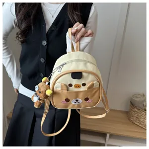 Cute bear plush pendant detail of mini backpack, soft fabric and embroidered cartoon design.