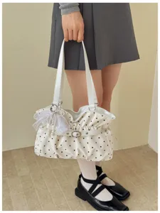 Dettaglio borsa a tracolla a pois con fiocco in tulle, ciondolo di perle e fibbia chic.