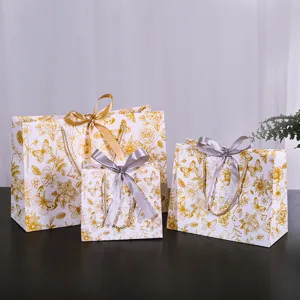 Elegante witte cadeautassen van papier met gouden bloemmotieven voor verpakking en detailhandel.
