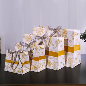 Cadeau papieren zakjes set met bloemenmotief en grijze strikken voor kleding en verpakking.