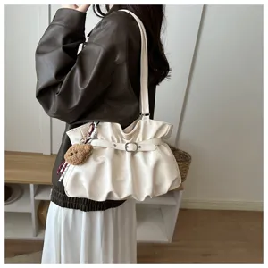 Vista detallada del elegante bolso de hombro plisado con hebilla chic y colgante de oso.