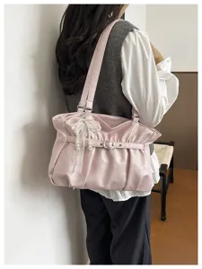 Dettaglio borsa a spalla rosa plissettata, design nuvola elegante con fiocco di perle e fibbia.