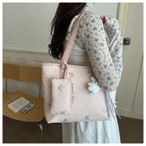 Detail view of a chic pink shoulder tote bag featuring glitter butterfly prints and a plush charm.