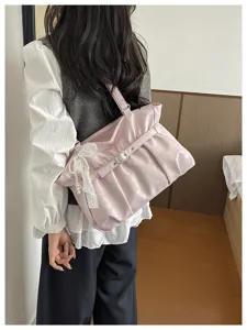 Dettaglio borsa a tracolla arricciata rosa, design elegante con ciondolo di perle per le donne.