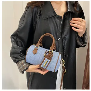Detailed view of women retro denim Boston handbag with brown leather handles and casual crossbody design.